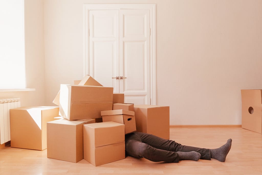 Person feeling overwhelmed by stacks of moving boxes
