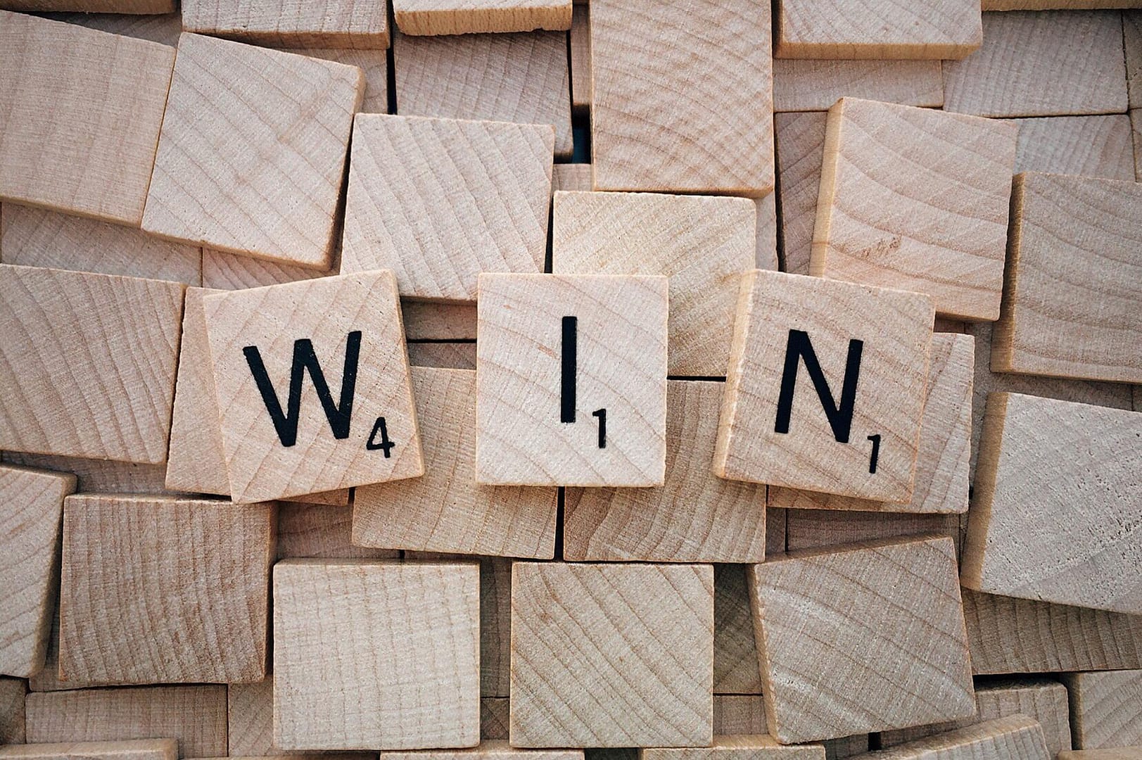 Wooden letter tiles spelling “WIN”
