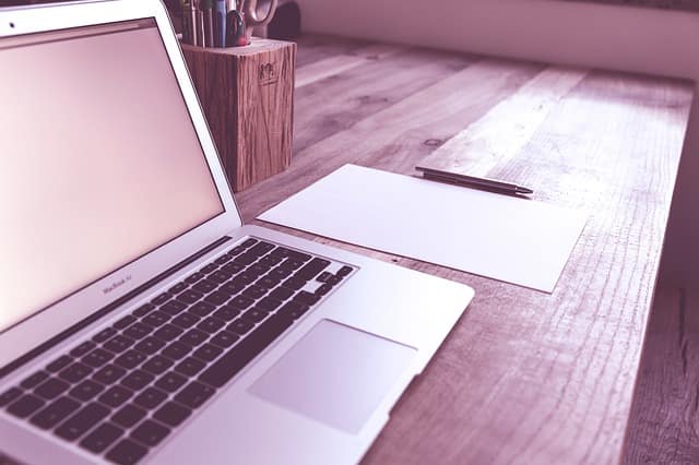 Laptop and notepad arranged on a wooden desk